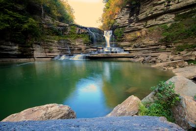 Cummins Falls descending into a broad green pool between layered cliffs.
