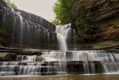 Cummins Falls flowing across stepped rock ledges beneath the gorge wall.
