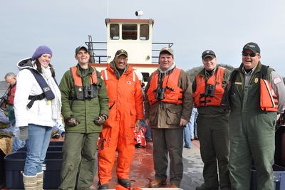 Six Eagle Watch crew members in life jackets standing on a boat deck.