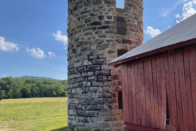 Stone chimney beside a red wooden outbuilding.